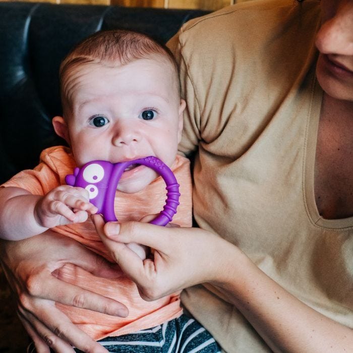Mum holding baby who is chewing on Kalani sensory mini teether