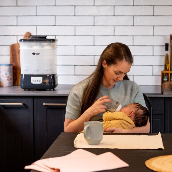 Woman feeding her baby in the kitchen with a Steridryer behind her