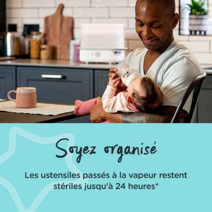 Père nourrissant son bébé dans une cuisine avec stérilisateur à vapeur blanc en arrière-plan et texte sur l&apos;organisation