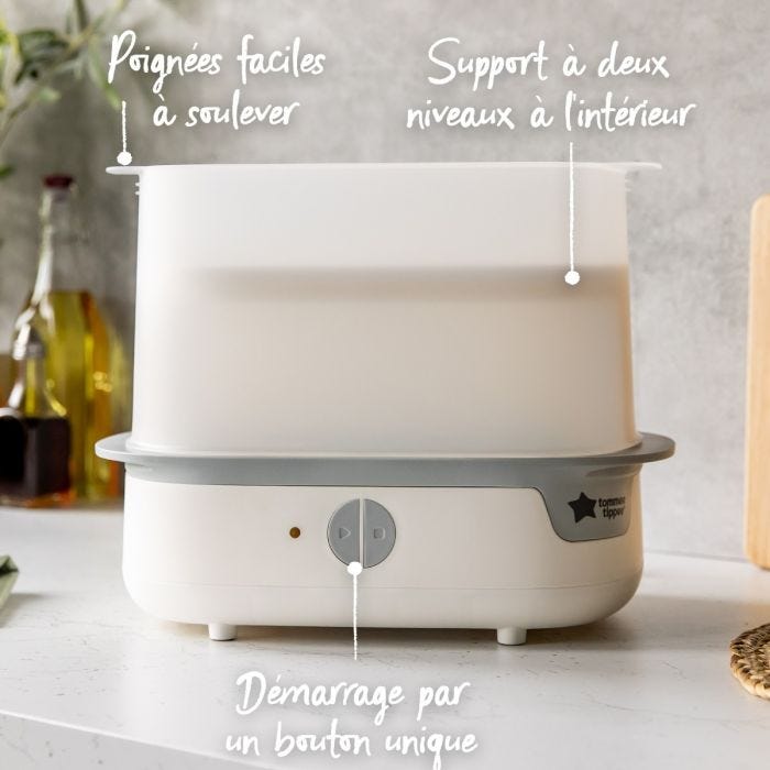 Stérilisateur à vapeur blanc sur plan de travail avec flèches sur poignées, démarrage à bouton unique et support deux niveaux