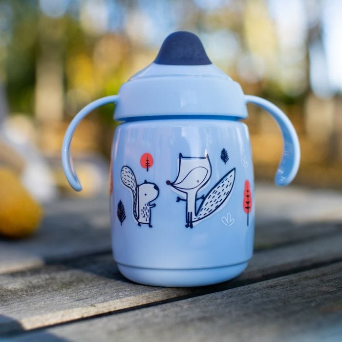 blue superstar training sippee cup placed on wooden bench outdoors