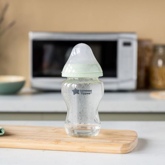 Glass baby bottle filled with steam on a kitchen counter