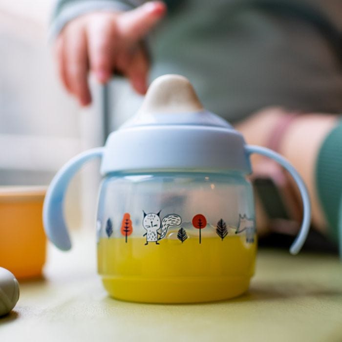 Tasse de sevrage bleue, remplie de jus d&apos;orange