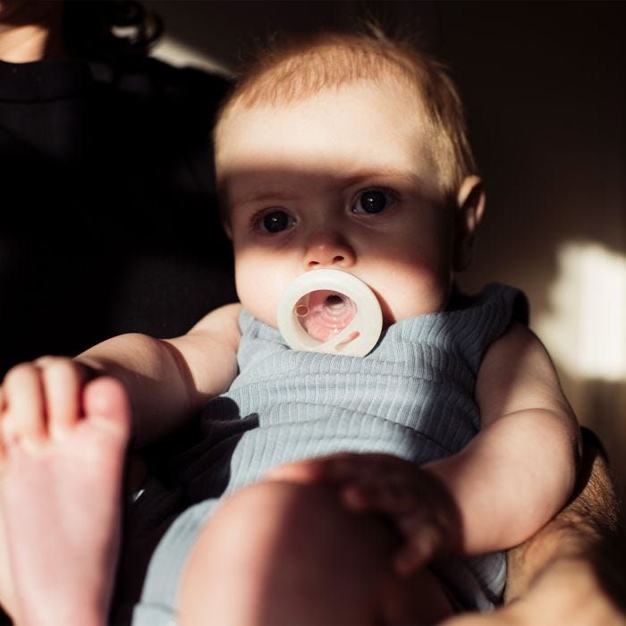 Baby with pacifier in mouth with shadow over face