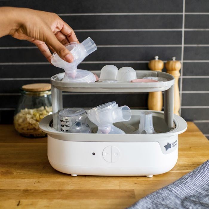 Woman placing separated parts of the electric pump in an electric steam steriliser