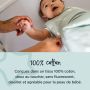 bébé couché souriant pendant que le parent ajuste le lange d&apos;emmaillotage avec un texte sur sa fabrication 100 % coton