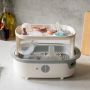 Open white steam sterilizer on a kitchen counter with breastfeeding accessories inside