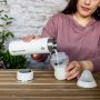 Woman pouring a freshly made formula feed into a sterile baby bottle