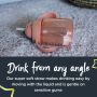 Pink weighted straw cup lying flat on a carpet with text about drinking from any angle