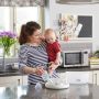 Mom holding baby and removing clean baby bottle from microwave sterilizer