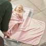 Bébé sur matelas à langer, enveloppé dans la serviette rose à capuche hug n dry.