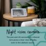 Parent unit on side table next to mug and plant with text explaining that it has a night vision camera.