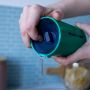 Someone pressing the valve of a teal 360 cup to show how the water is released