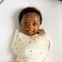 Bébé portant une gigoteuse d&apos;emmaillotage rose allongé sur le dos avec un bras en dehors de la gigoteuse et un bras dedans.