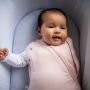 Bébé portant une gigoteuse d&apos;emmaillotage crème avec un imprimé étoile et lune avec les deux bras dans la gigoteuse.