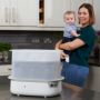 Stérilisateur à vapeur blanc sur le plan de travail avec maman et bébé debout derrière