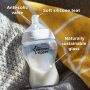 Glass baby bottle on windowsill with pointers to its silicone teat, anti-colic valve and sustainable glass base