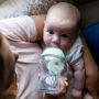 Mum feeding baby from glass baby bottle