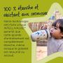 Jeune enfant buvant dans sa tasse sportee grise, avec un texte disant qu&apos;elle est 100 % étanche et résistante aux secousses