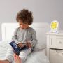 boy sitting on bed reading groclock book with groclock on bedside table
