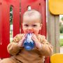 Little boy drinking from a blue sippee cup while at the playground