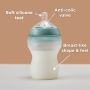 Silicone baby bottle on a table with pointers to its silicone teat, anti-colic valve and breast-like shape