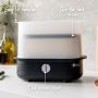 Black steam steriliser on kitchen counter with pointers to its easy-lift handles, one-button start and two-tier rack