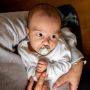 Baby with Night-Time pacifier in mouth being cradled in mom’s arms.
