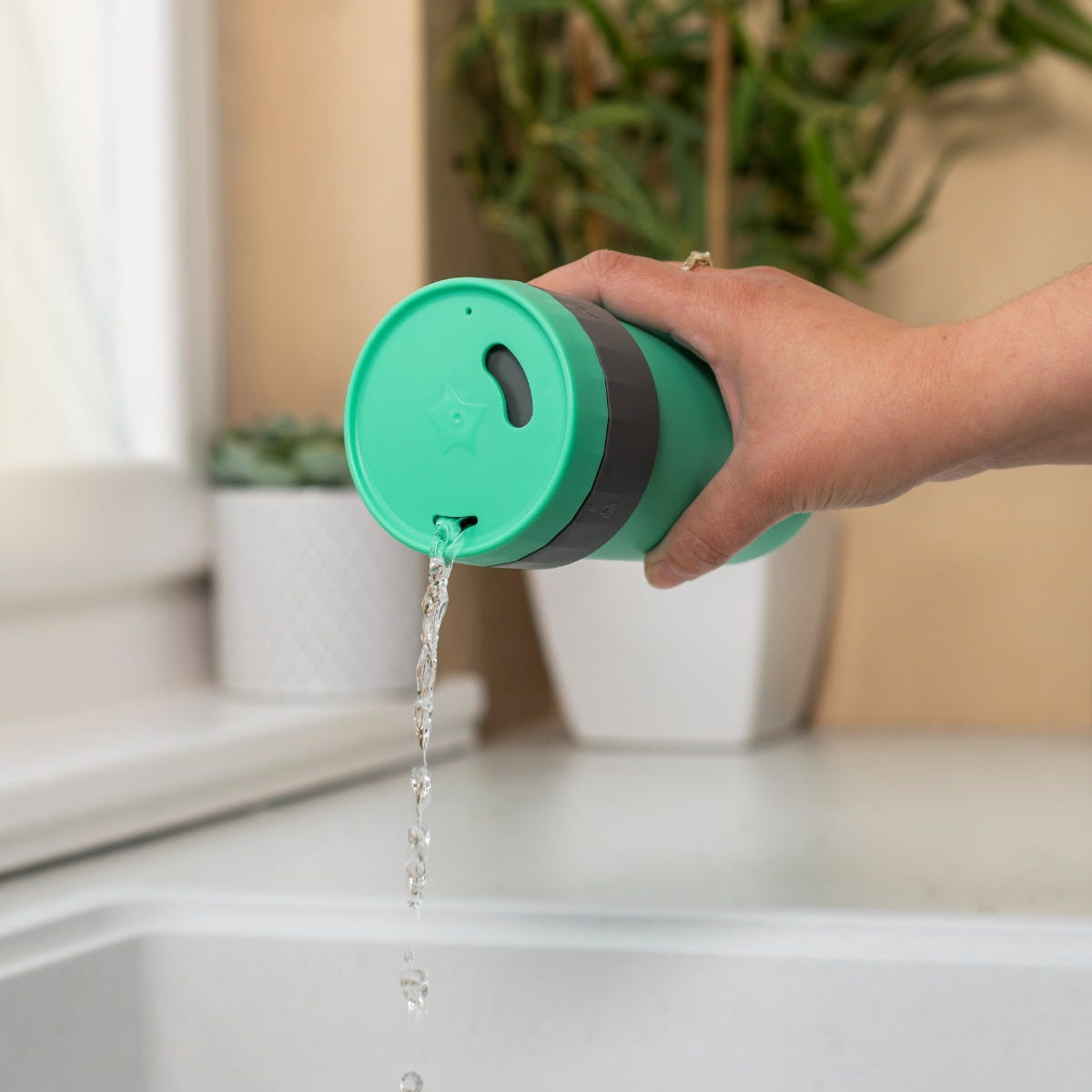 Someone holding their 3in1Cup over the sink to show how water flows freely from the freeflow opening