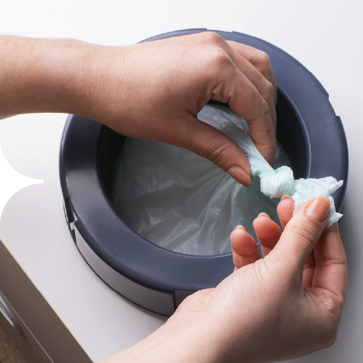 Un parent terminant la deuxième étape du rechargement de sa poubelle à couches Twist & Click.