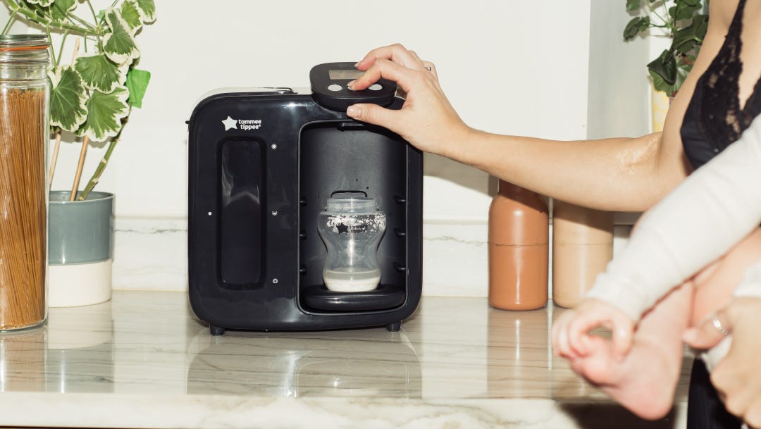 a mum using a Tommee Tippee Perfect Prep machine to make a bottle of formula for her baby 