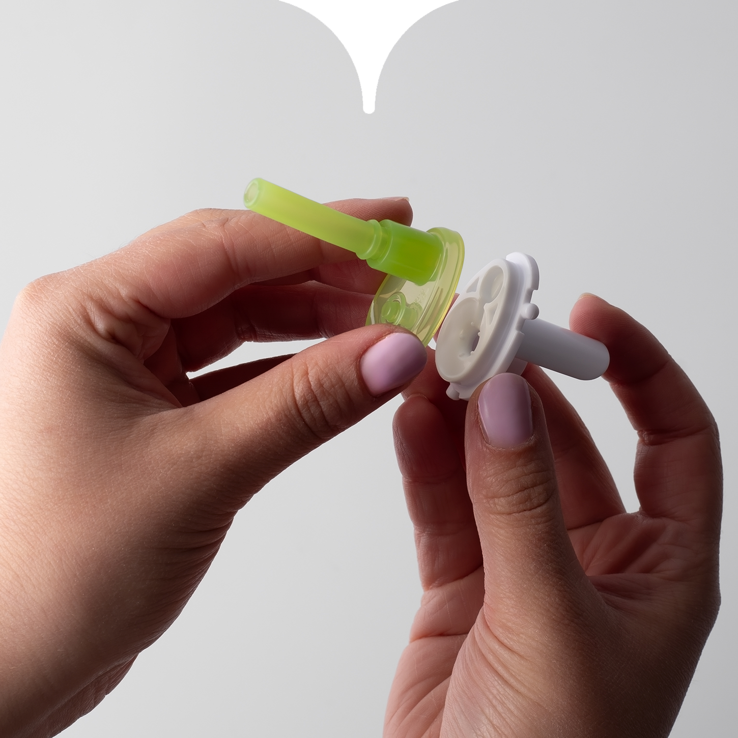 Close up image of hands aligning the two connecting pieces of a Tommee Tippee straw cup valve.