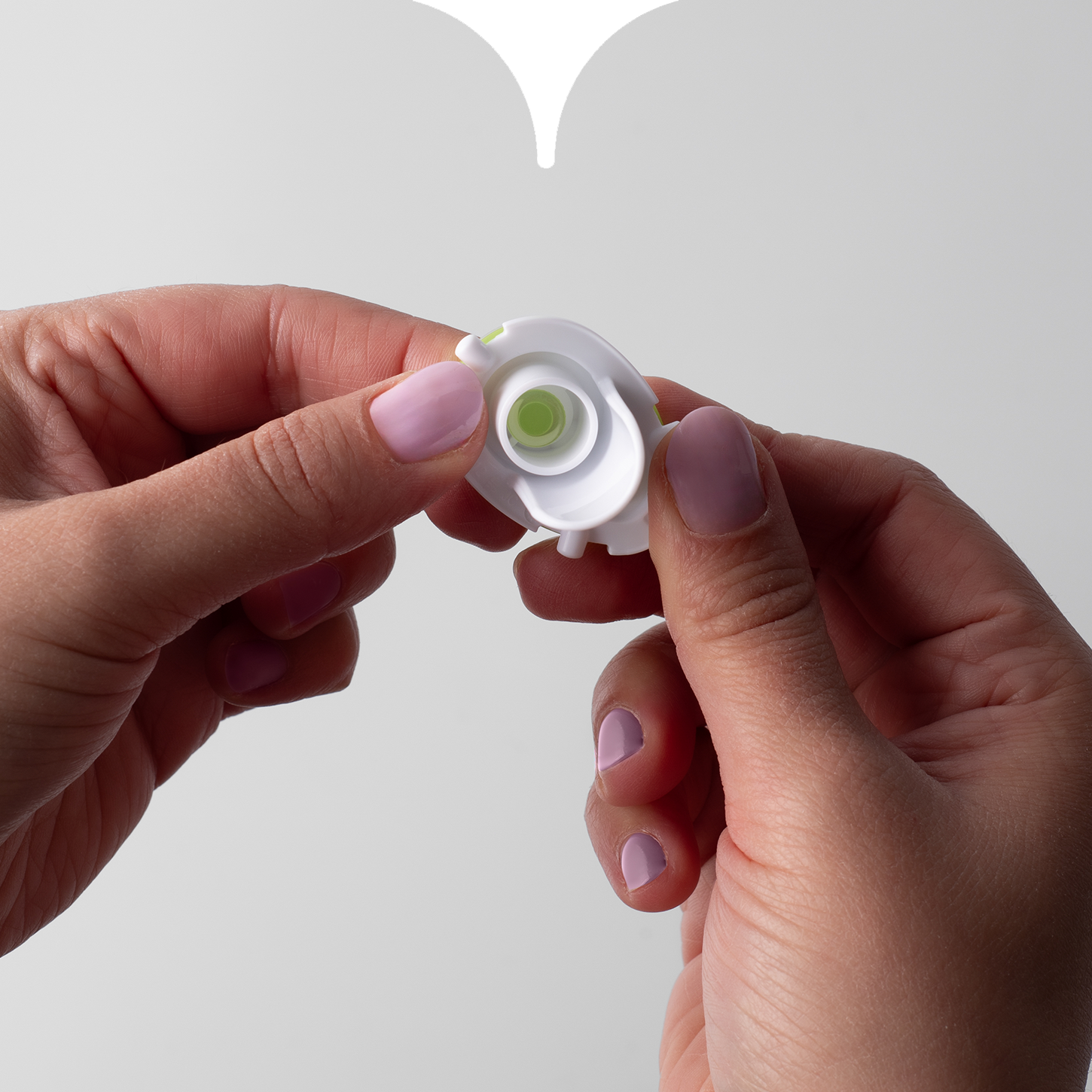 Close up image of hands connecting the two pieces of a Tommee Tippee straw cup valve together. 