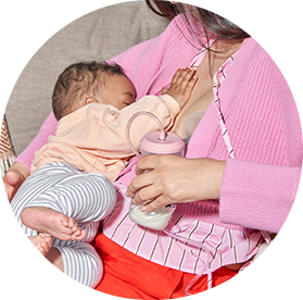 A mum feeding her baby using a tommee tippee wearable breast pump