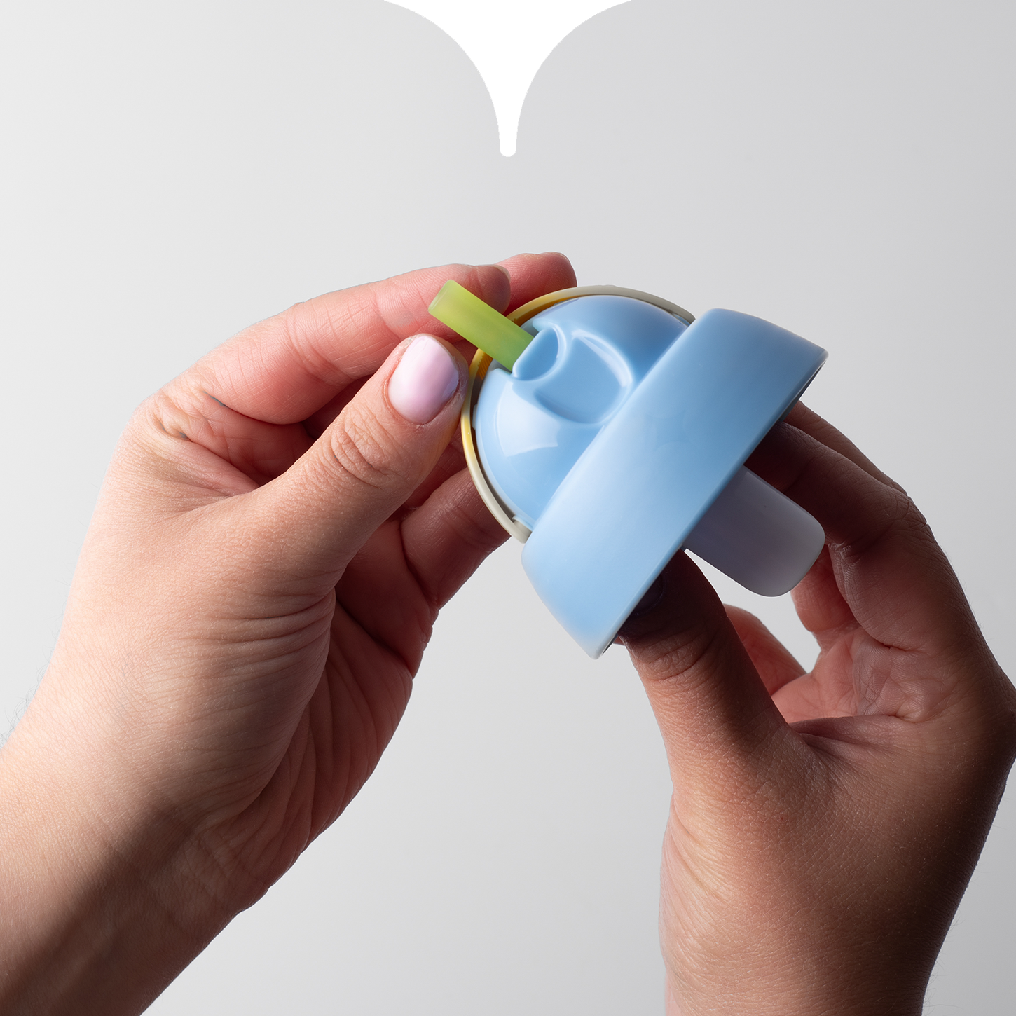 Close up image of hands attaching the soft straw (and connecting cup valve) through a Tommee Tipppe cup lid. 