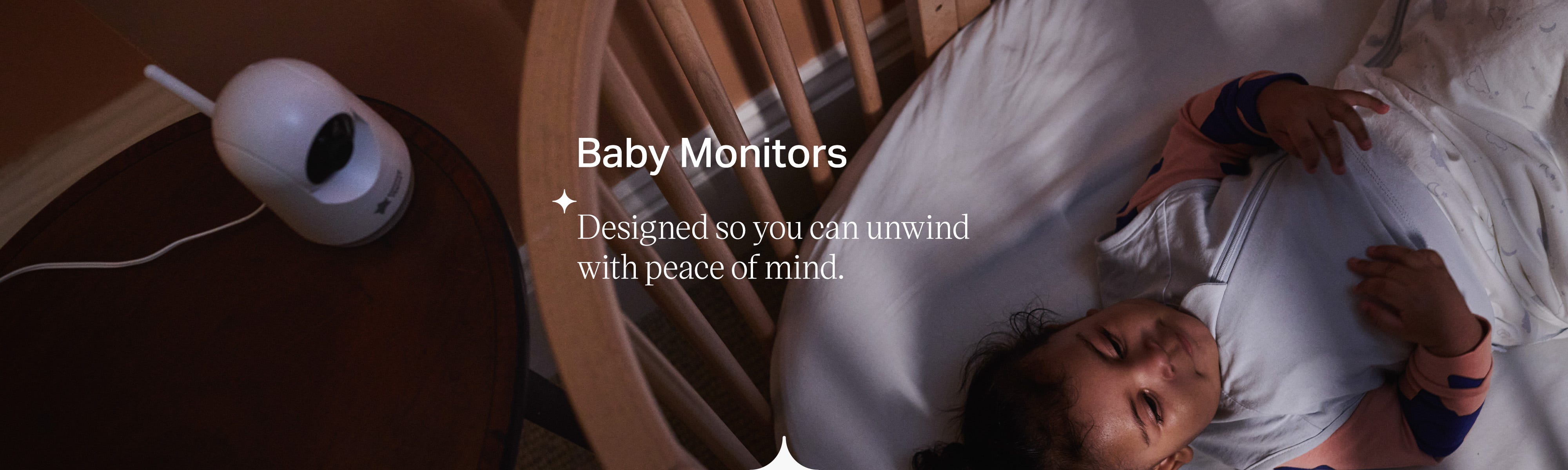 A baby lying in their cot being watched by a baby sleep monitor. 