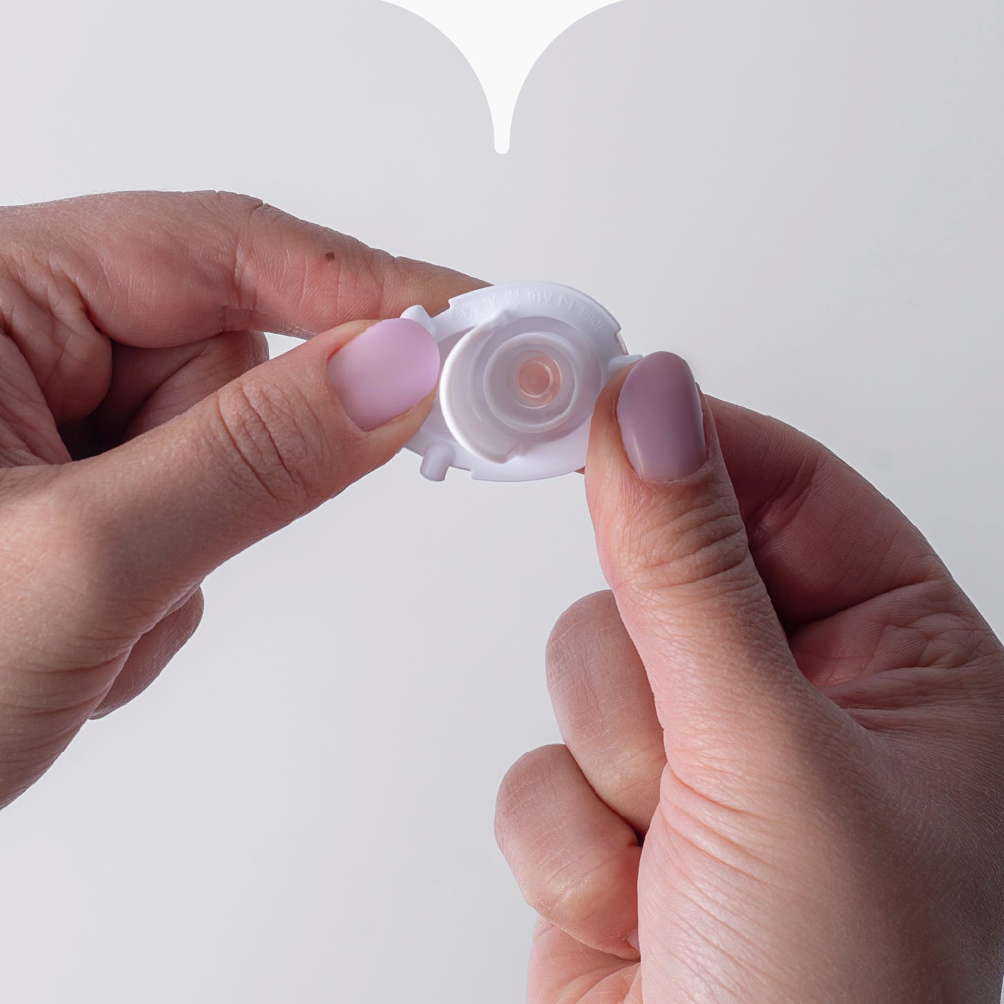 Close up image of hands connecting the two pieces of a Tommee Tippee straw cup valve together. 