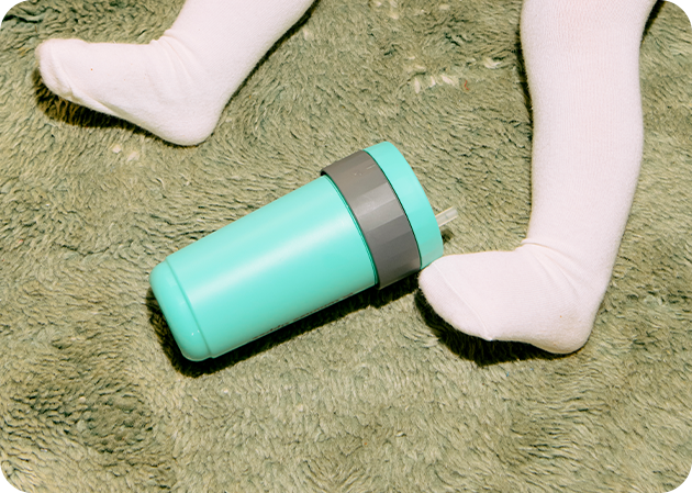 A blue Tommee Tippee cup on a green carpet. 