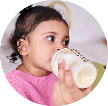 A toddler drinking from a tommee tippee baby bottle.